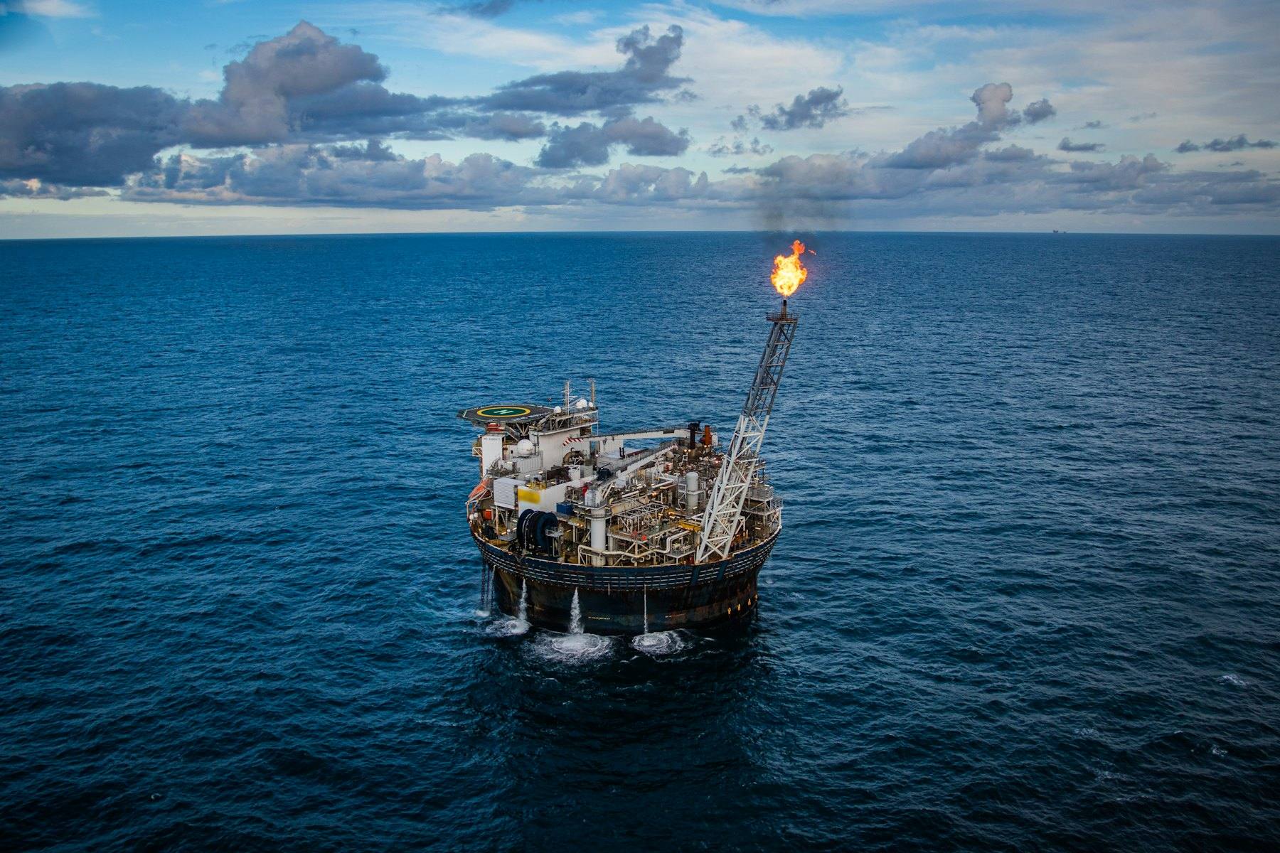 Aerial view of a floating production vessel with its flare lit
